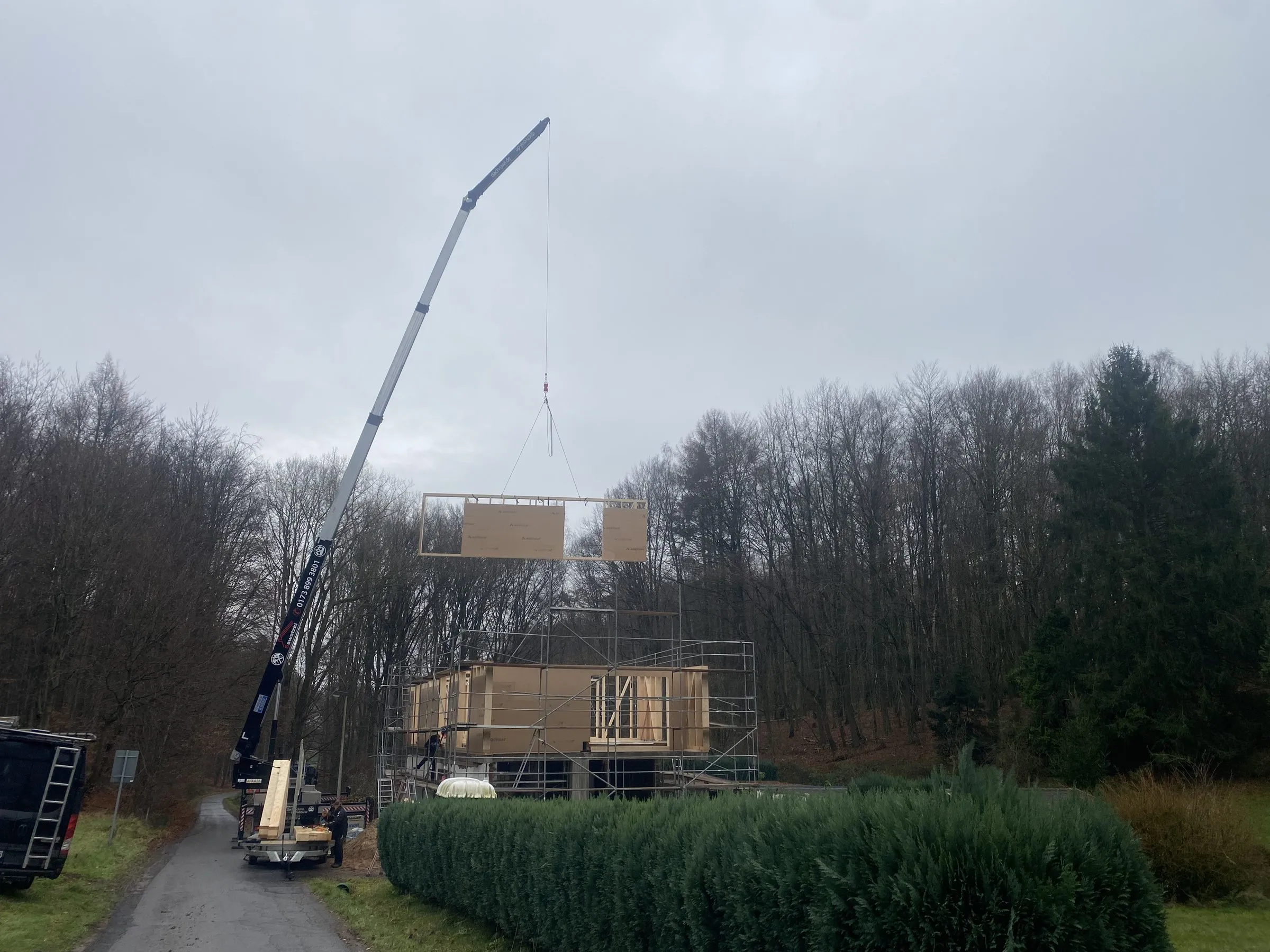 Kran hebt ein vorgefertigtes Wandelement für die Aufstockung eines Bestandsgebäudes