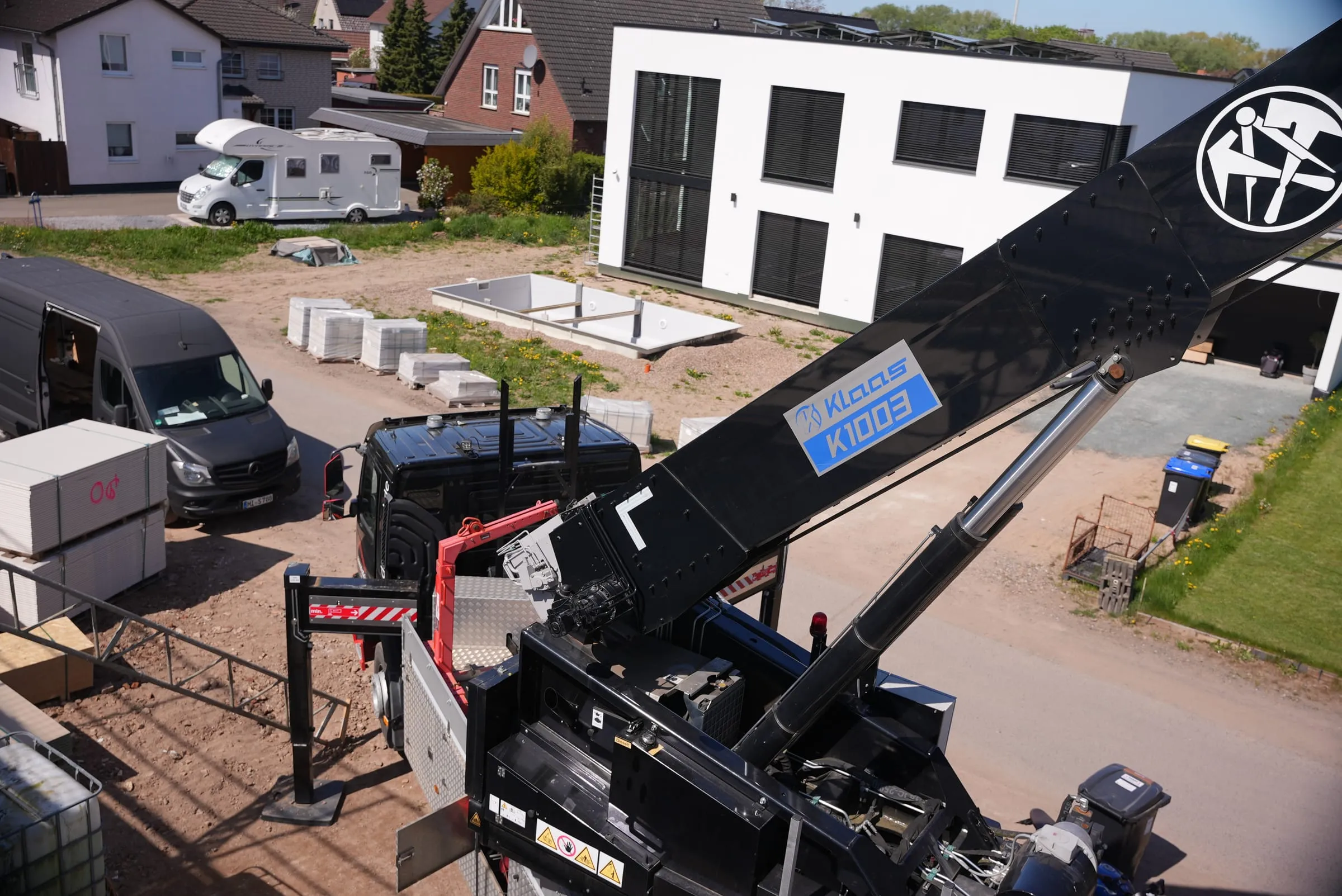 Ausleger des Autokrans über einer Baustelle im Neubaugebiet mit bereitgestelltem Material