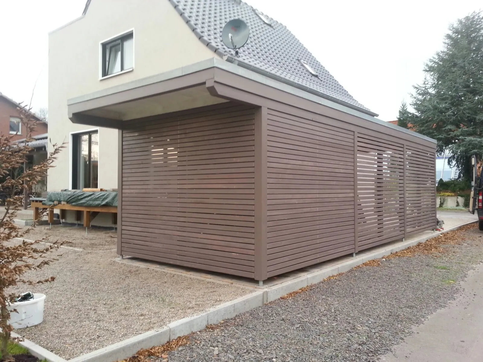 Moderner Carport mit Lamellen-Bekleidung an einem Wohnhaus