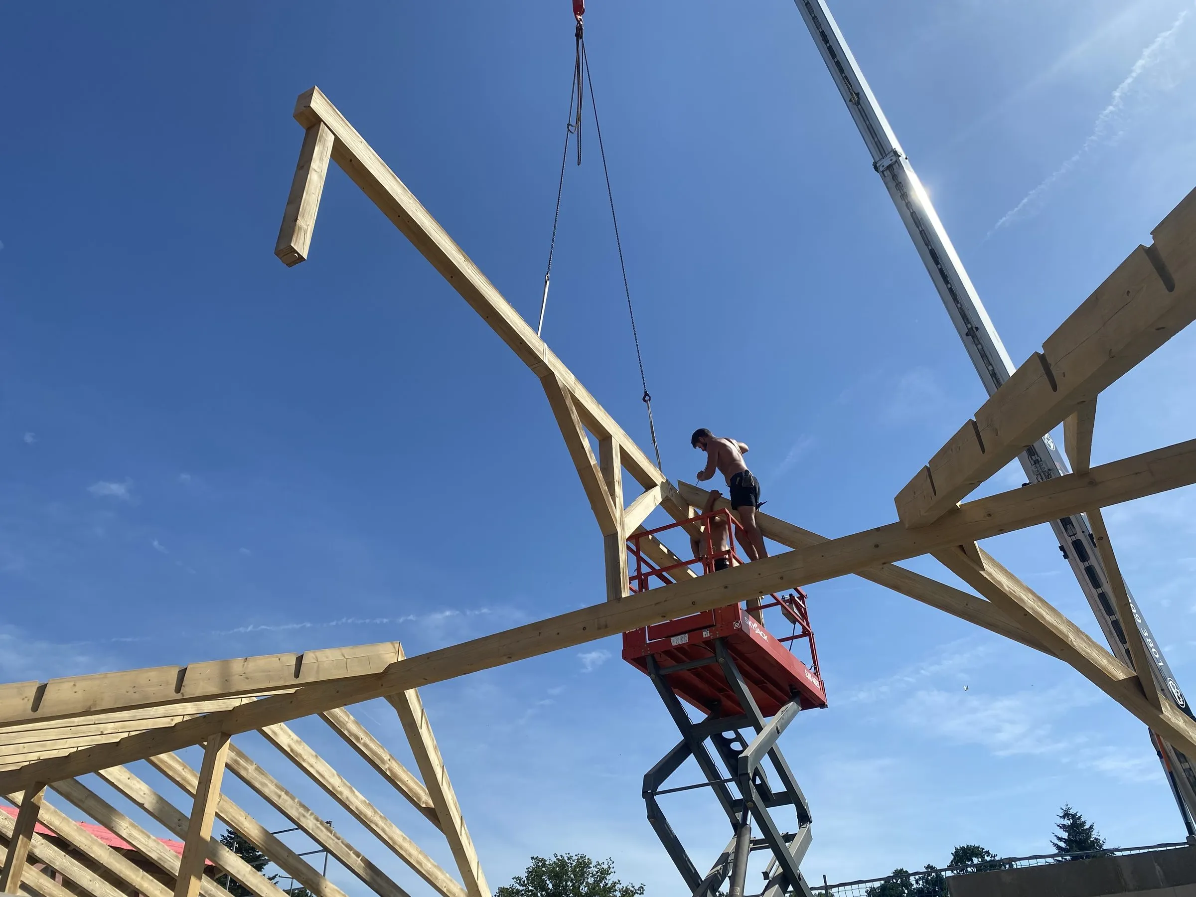 Binder hängt am Kranhaken über einer Dachbaustelle
