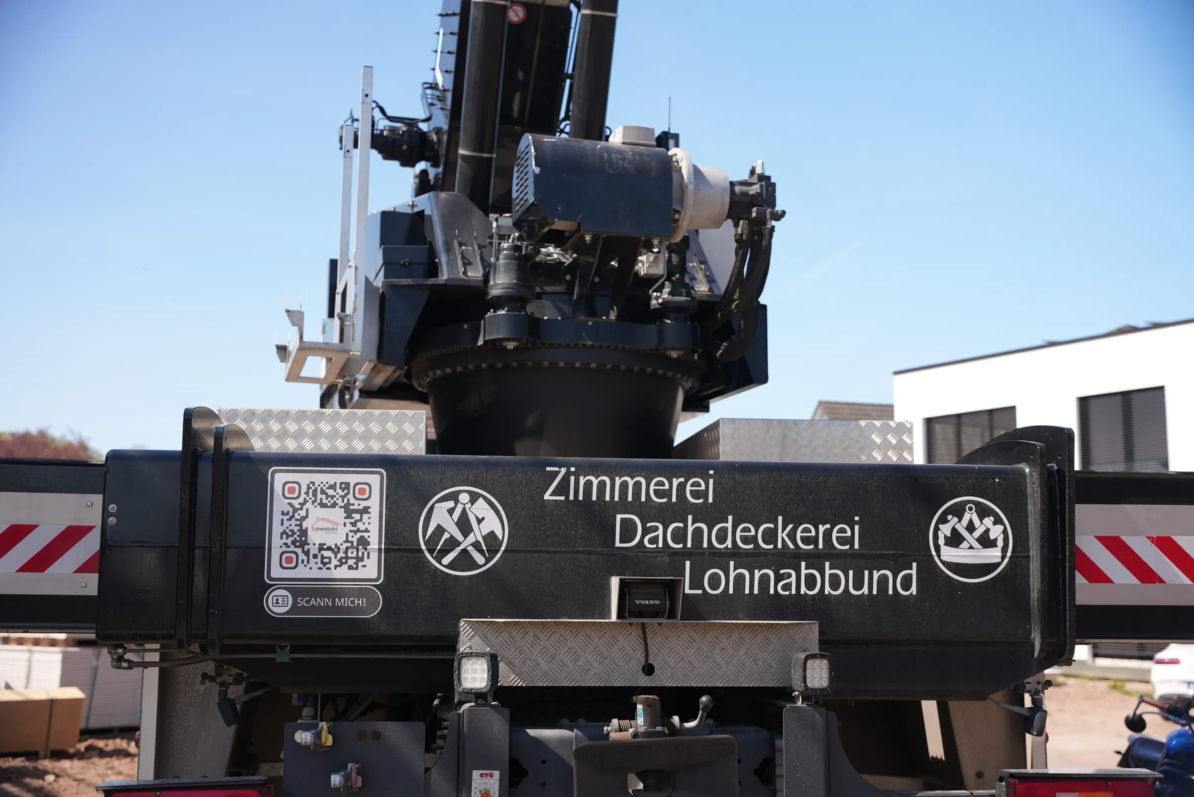 Detail des Kranwagens der Sawatzki GmbH mit Zimmerer- und Dachdecker-Emblem am Ausleger