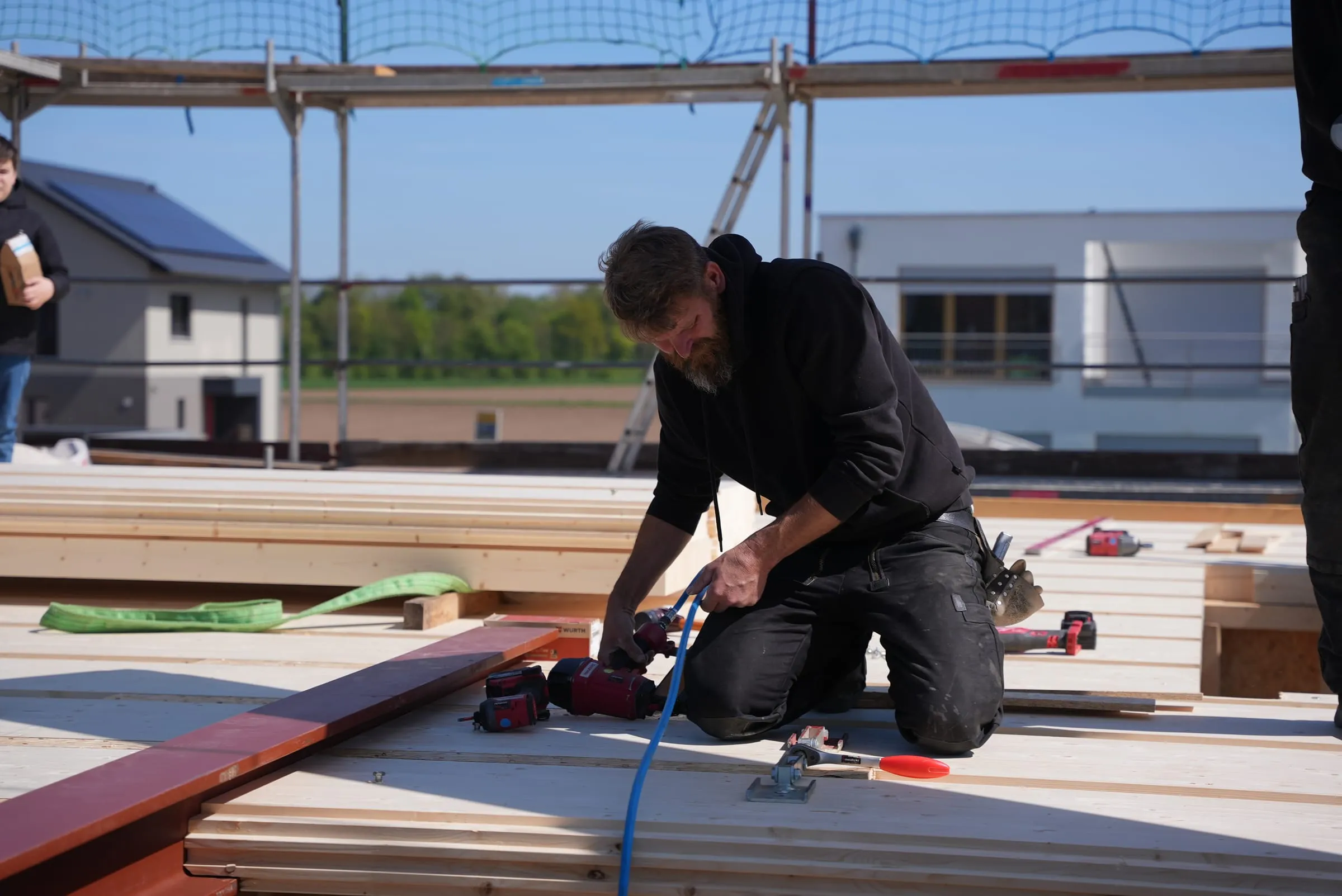 Zimmerer befestigt mit dem Druckluftnagler ein Holzelement bei der Montage