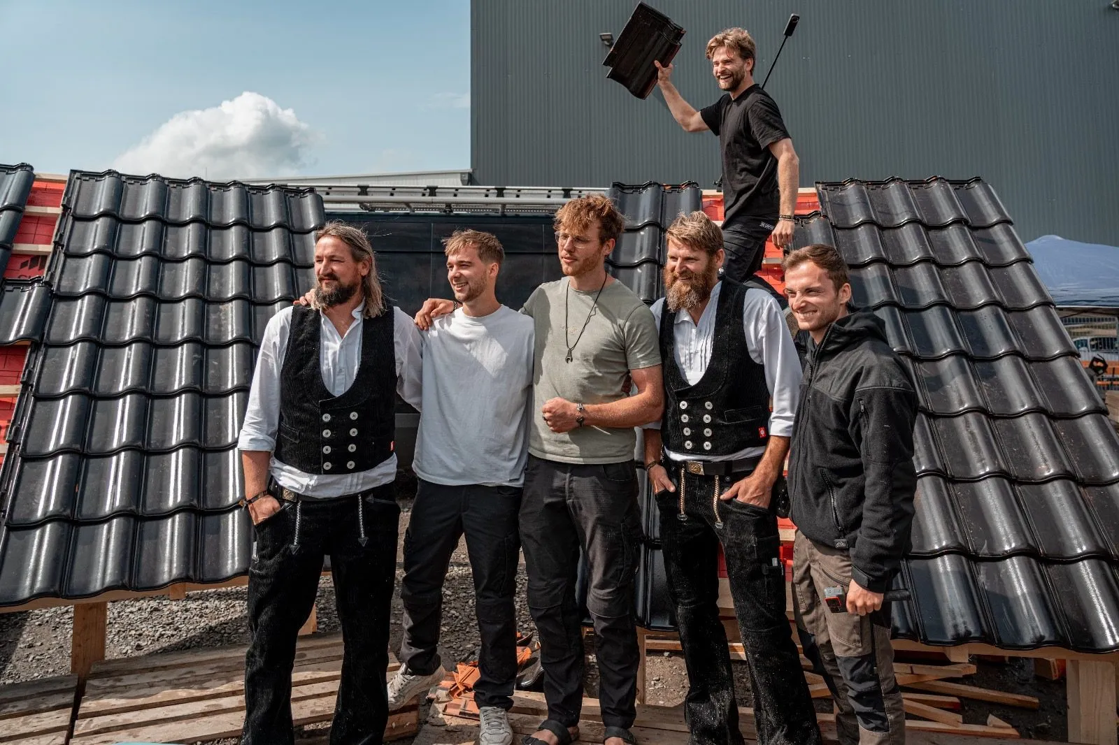 Mitarbeiter der Sawatzki GmbH in Zunftkleidung vor der Musterwand mit Dachziegeln