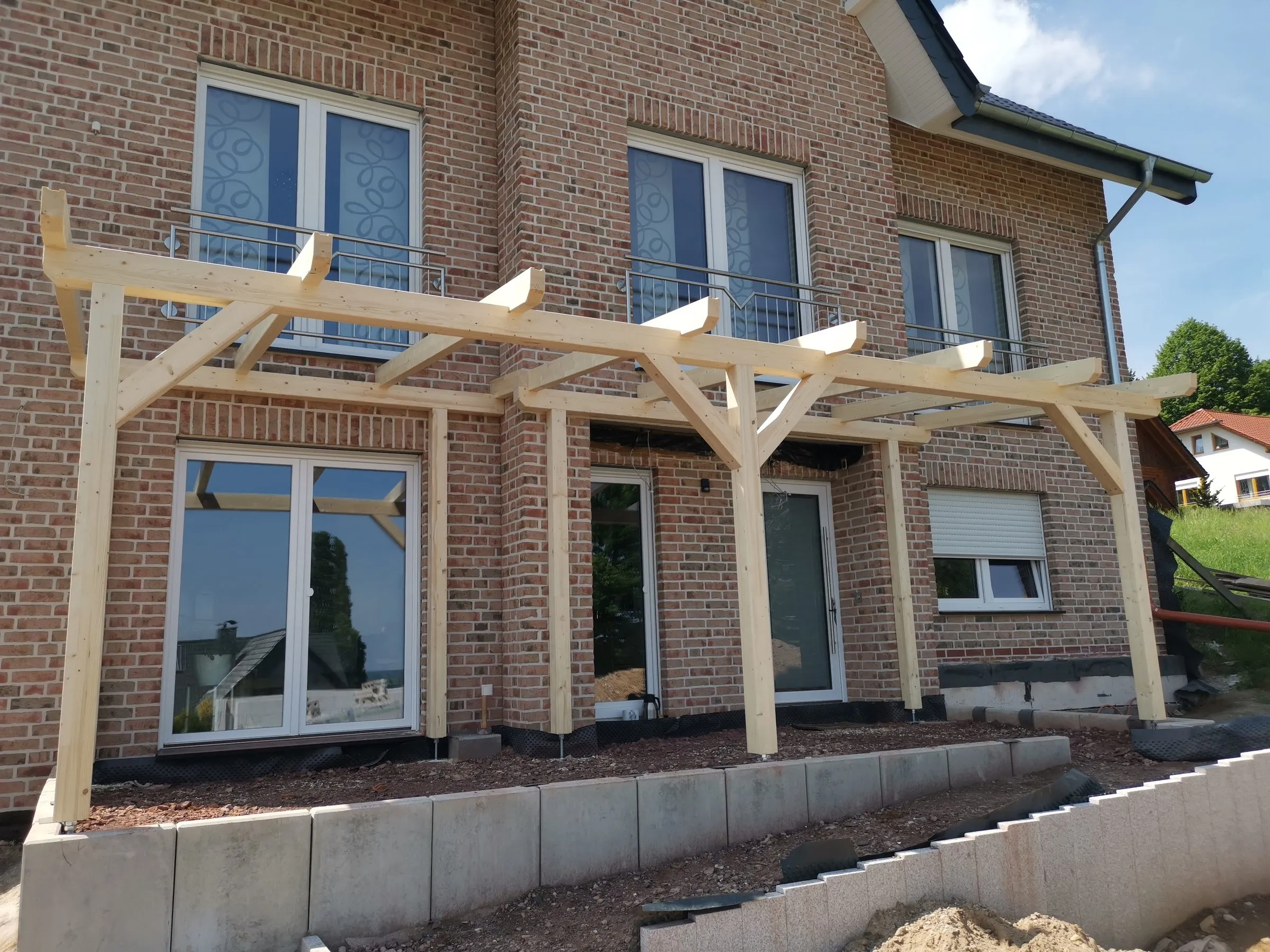 Holzkonstruktion einer Terrassenüberdachung vor der Fensterfront