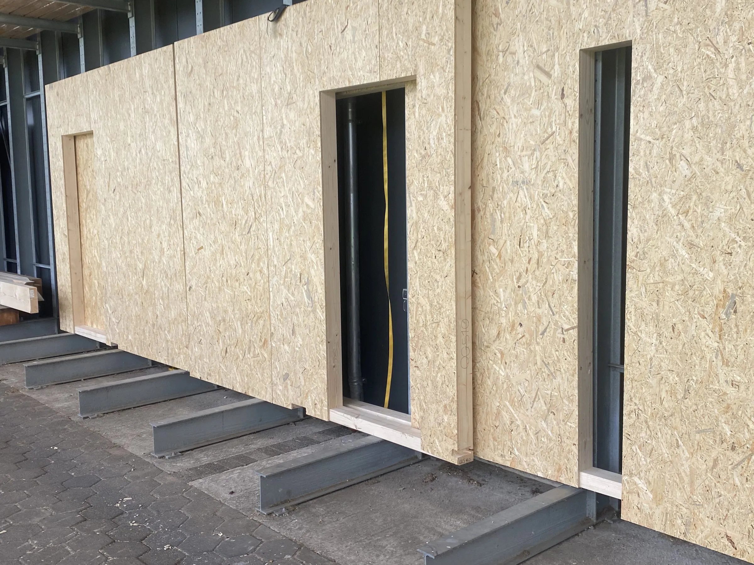 Vorgefertigtes Wandelement mit Fensteröffnungen und Beplankung in der Fertigungshalle der Sawatzki GmbH